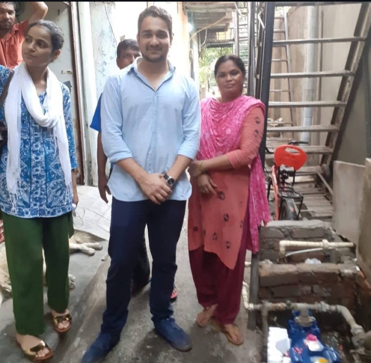 Residents of Indira Gandhi Camp standing beside the newly installed community water pump